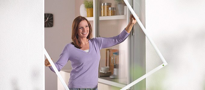 Frau bringt Insektenschutzrahmen in Fenster an