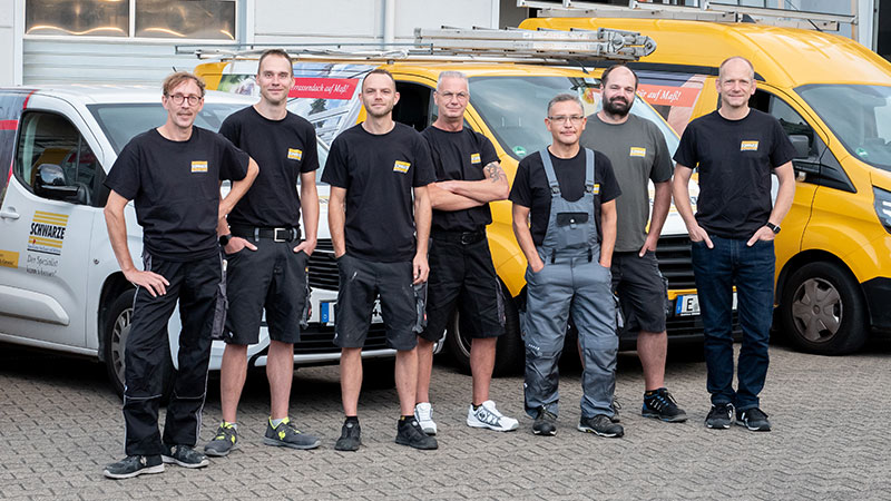 Montage-Team steht vor den Firmenfahrzeugen